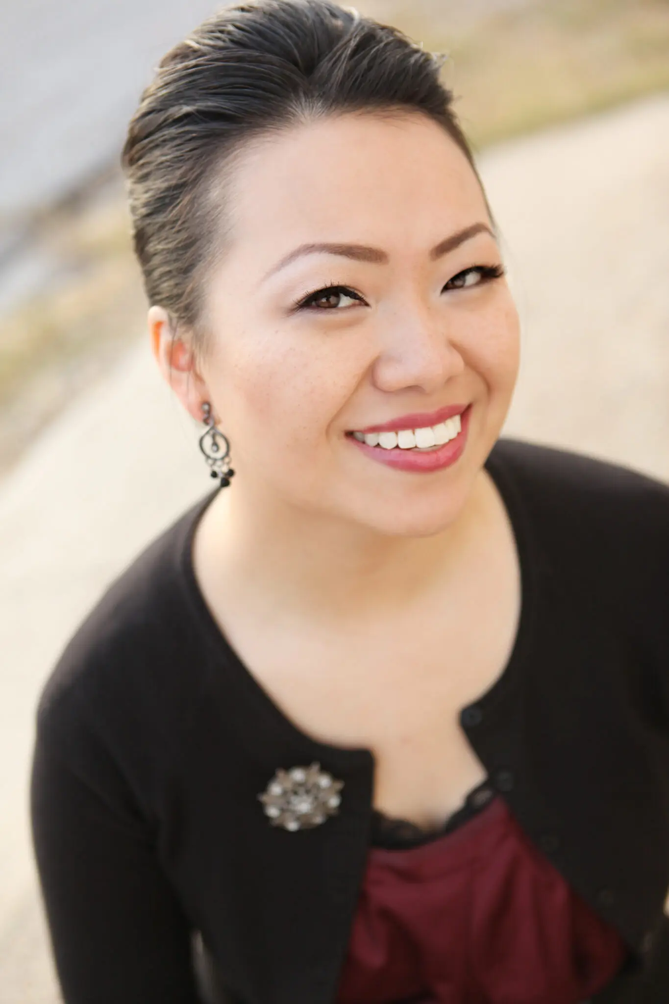 Smiling woman wearing earrings and cardigan.